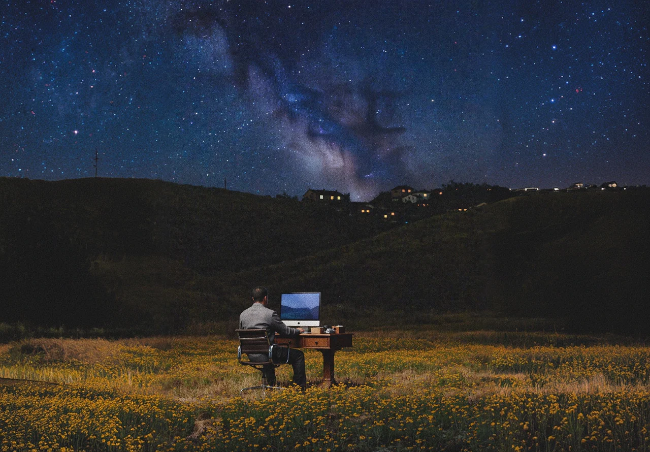 A desk and screen in a flower field under the stars