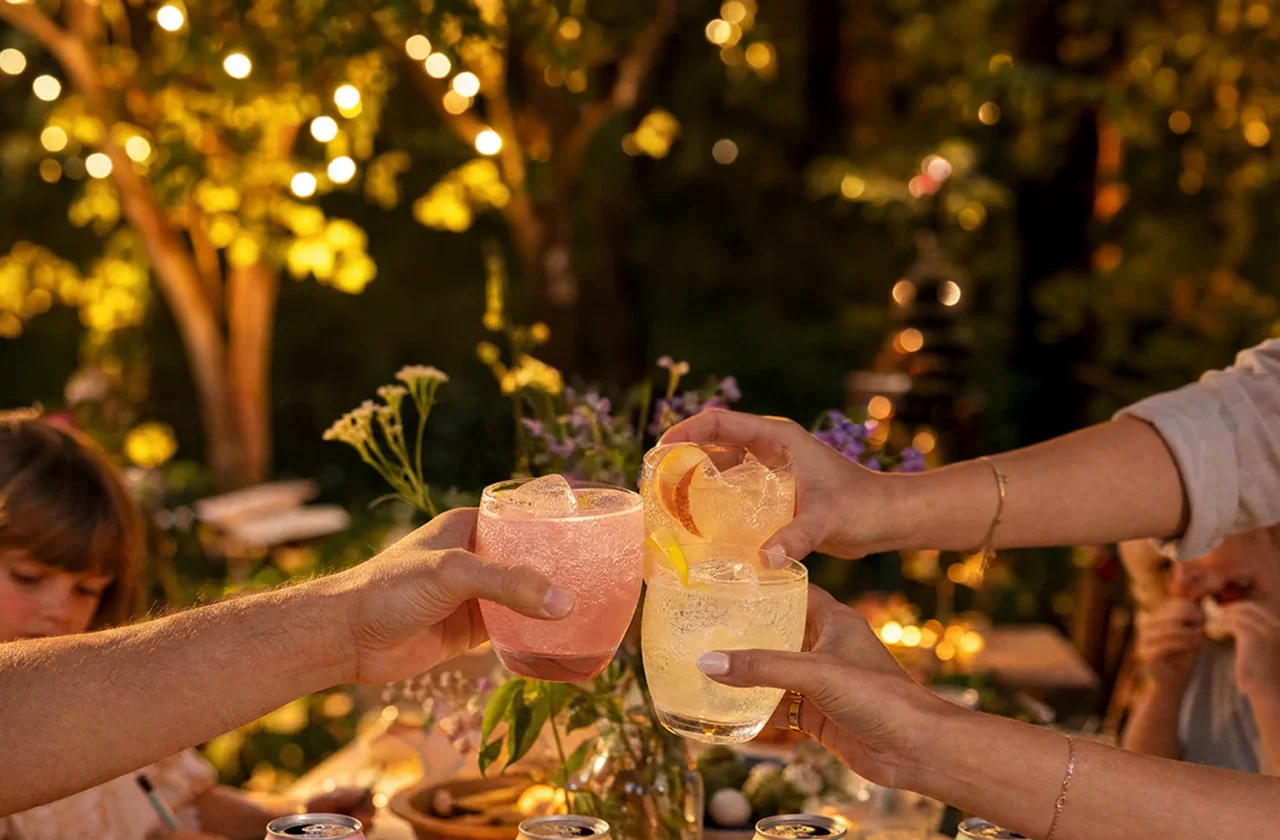 Friends raising glasses around a table with pastel TRIP cans
